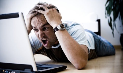 Photo d'un homme horrifié devant son ordinateur portable
