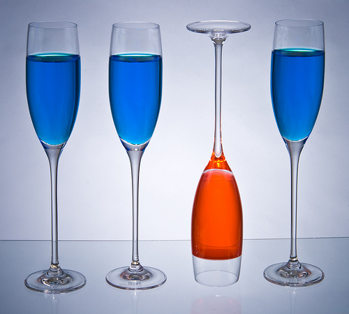 Photo de 3 verres remplis d'un liquide bleu, et d'un rempli d'un liquide rouge, posé à l'envers.