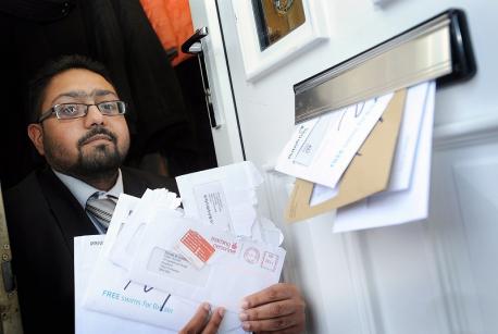 Photo d'un homme et sa boite aux lettres débordant de courrier